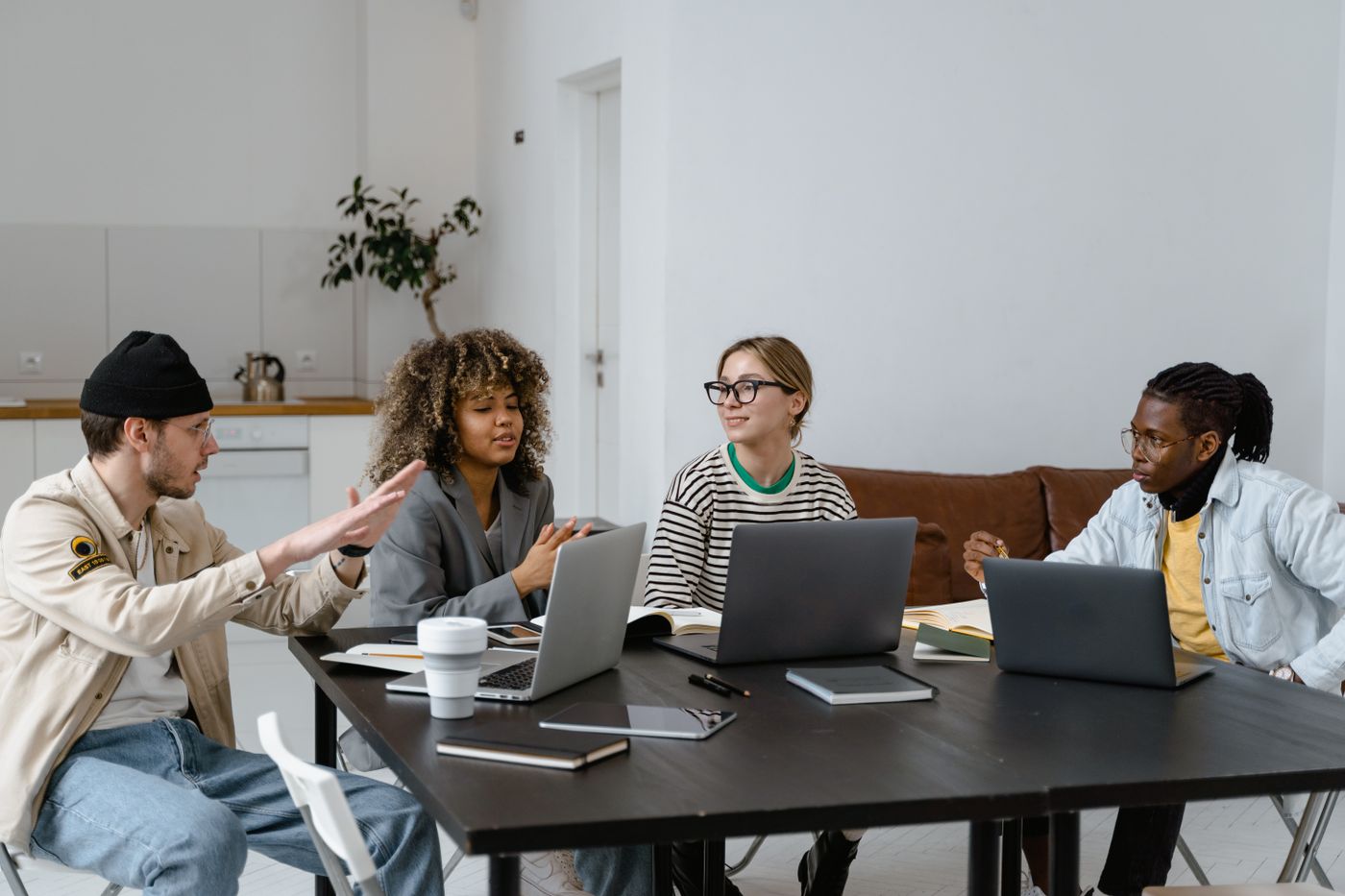 Diverse startup team collaborating around a table with laptops